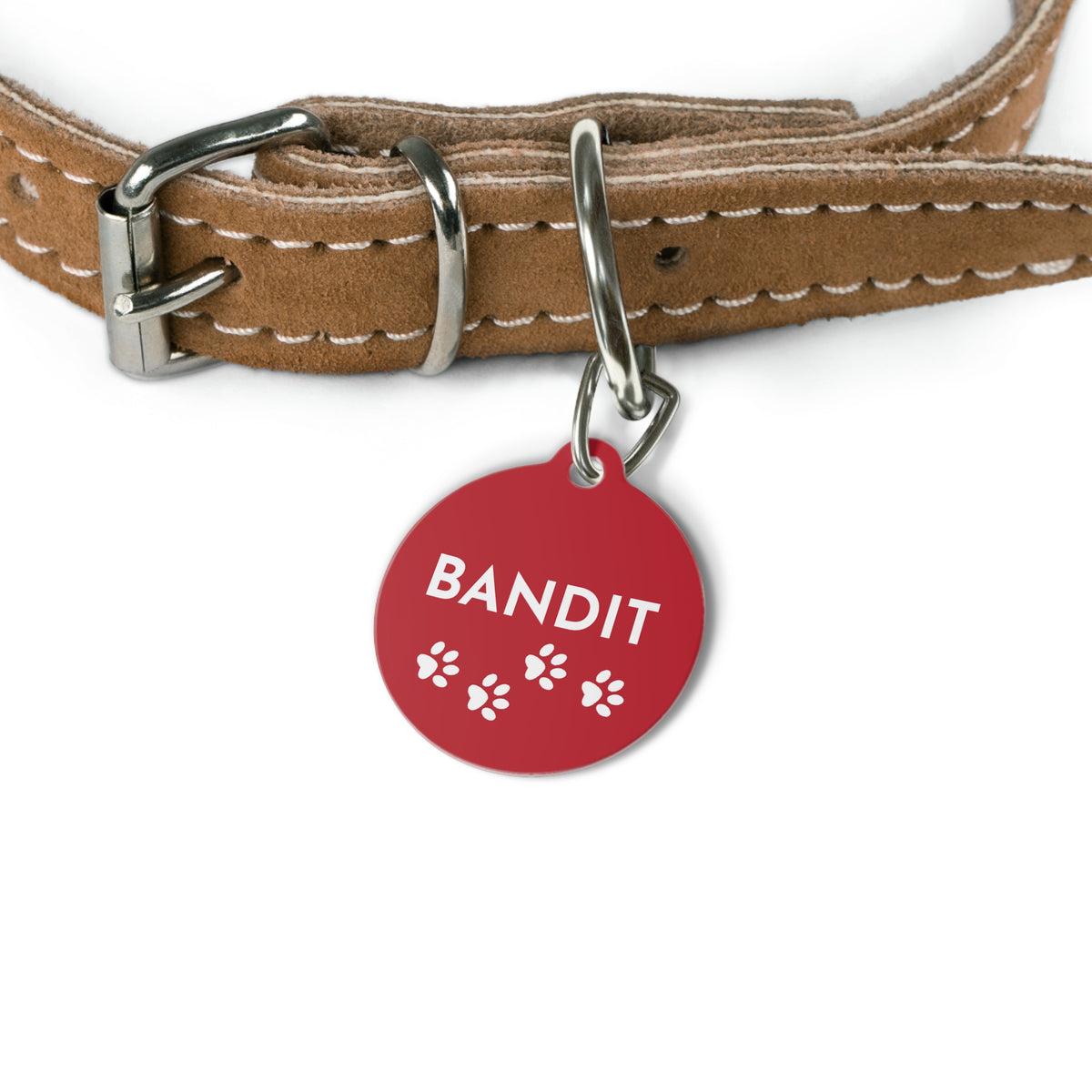 Red paw print personalized dog tag with name Bandit hanging from a tan leather dog collar
