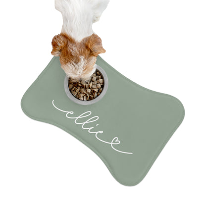 Dog eating from a bowl on a sage green bone-shaped personalized feeding mat, seen from above