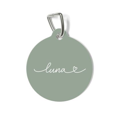 Round sage green personalized pet tag with the name Luna in white handwritten script and a small heart