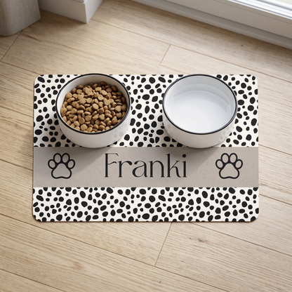 Spotted paw personalized pet food mat with the name Franki holding a food bowl and a water bowl on a wooden floor