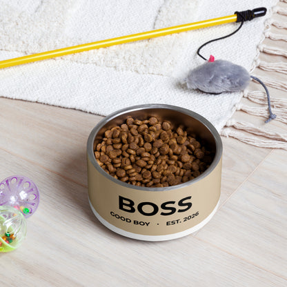 Tan good boy personalized dog bowl filled with kibble on a rug next to a pet toy