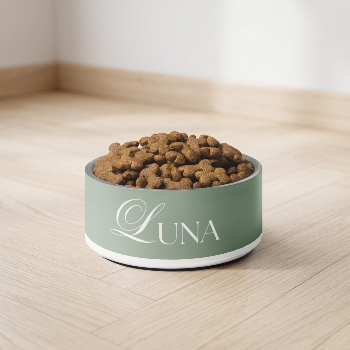 Thyme green personalized dog bowl filled with kibble on a light wooden floor