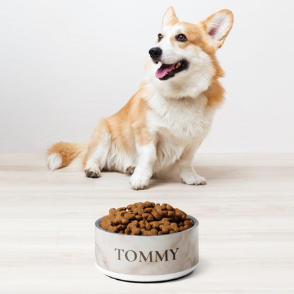 Corgi sitting next to a white marble personalized dog bowl filled with kibble