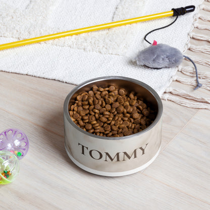 White marble personalized dog bowl with the name Tommy on the floor next to a leash