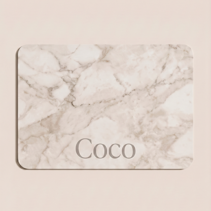 White marble personalized pet food mat with the name Coco on a beige background