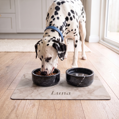 Dalmatian eating from a bowl on a white marble personalized pet food mat with the name Luna